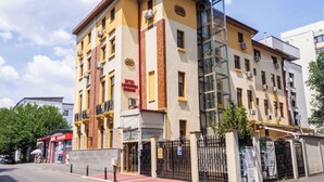 A multi-story hotel with a yellow facade, a restaurant on the ground floor, and a visible elevator shaft. - Hotel Amphitryon Premium (Bucharest)