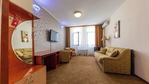 A hotel room with a sofa, armchair, TV, and a mirror. - Hotel Amphitryon Premium (Bucharest)