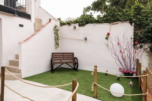 A small outdoor area with a wooden bench, a rope obstacle course, and a white spherical object.