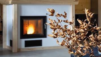 A modern living room with a fireplace, a wooden mantel with animal figurines, and a vase with dried leaves.