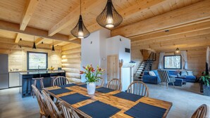 Un interior de cabaña de madera espacioso, con comedor, cocina y sala de estar.