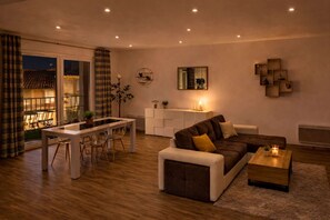 A modern living room with a sofa, coffee table, and dining area.