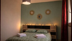 A bedroom with a bed, bedside tables, a lamp, wall decorations, and a window with curtains. - Les Clés de Laurent – 2-Bedroom Apartment, 70 m², Large Balcony, Downtown (Graulhet)