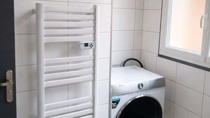 A laundry room with a white wall-mounted dryer and a front-loading washing machine. - Les Clés de Laurent – 2-Bedroom Apartment, 70 m², Large Balcony, Downtown (Graulhet)