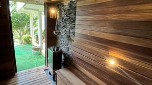 Un sauna en bois avec un mur en pierre et un banc.