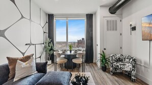 Moderni olohuone, jossa on ruokailutila, suuret ikkunat ja näkymä kaupunkiin.