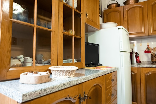 Une cuisine avec des meubles en bois, un réfrigérateur blanc et un four à micro-ondes.