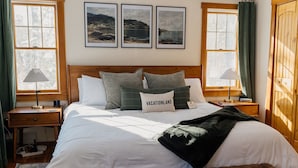 A neatly arranged bedroom with a large bed, a bedside table, a lamp, and a bench. - Pemaquid Escape | Curated Comfort + Hot Tub (Walpole)