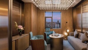 A modern lounge with a round coffee table, plush seating, a vase of flowers, and a city view through a large window. - Crystal Orange Changsha IFS (Changsha)