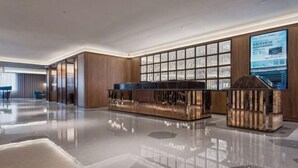 A modern lobby with a reflective floor, wooden paneling, a reception desk, and a large digital display. - Crystal Orange Changsha IFS (Changsha)