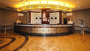 A reception area with a circular desk, patterned walls, and a marble floor. - Throne Beach Resort & Spa (Manavgat)
