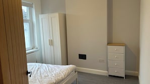 Et soveværelse med seng, garderobe, kommode og radiator.