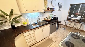 A kitchen with white cabinets, a black countertop, a sink, a stove, and a window with a view.