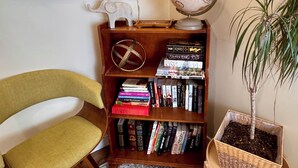 A corner room with a bookshelf, a globe, a framed map, a chair, and a potted plant.