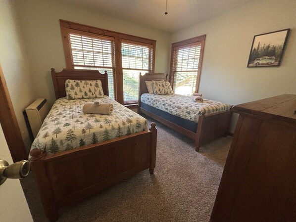 A bedroom with two wooden beds, a wooden dresser, and a framed picture on the wall.