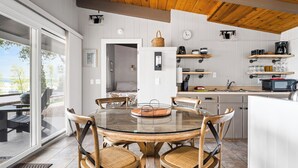 Una cocina moderna con una mesa de comedor de vidrio, sillas de mimbre y armarios de madera.