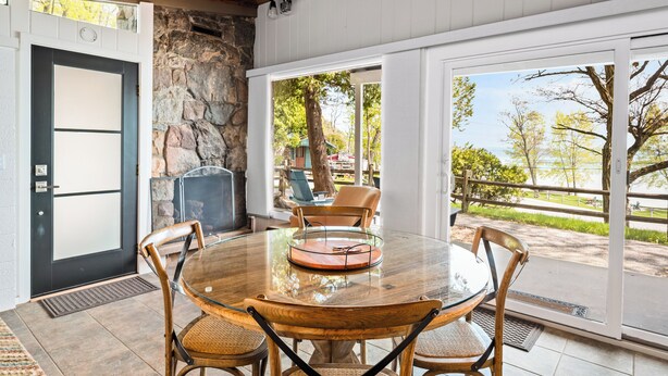 Un comedor con una mesa redonda de cristal, sillas de madera, una pared de piedra y vistas al exterior.
