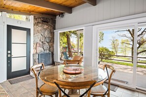 Un comedor con una mesa redonda de cristal, sillas de madera, una pared de piedra y vistas al exterior.