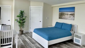 A bedroom with a bed, bedside tables, a chair, a potted plant, and a door. - The Lookout - Executive Class, Accessible Mini Villa (Colindale)