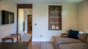 Un salon moderne avec un mur d’accent en briques, un canapé, une table basse et un téléviseur fixé au mur.