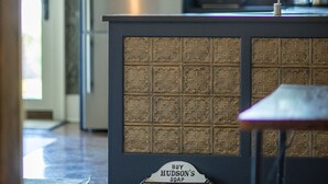 Une cuisine avec des meubles de couleur sombre, un réfrigérateur en acier inoxydable et un îlot central intégré doté d’un distributeur de savon.
