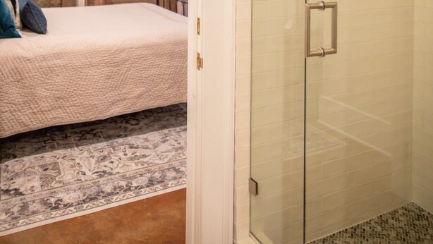 Une chambre avec un lit, un mur en pierre et une cabine de douche en verre.