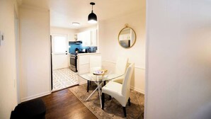 A modern kitchen with white cabinets, a blue backsplash, and a hanging pendant light. - Downtown Gem Close to Everything (Little Rock)
