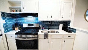 A kitchen with white cabinets, a black stove, and a blue-tiled backsplash. - Downtown Gem Close to Everything (Little Rock)