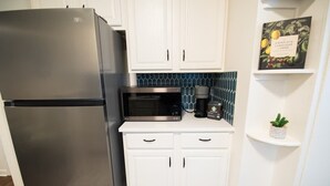 A kitchen with white cabinets, a stainless steel refrigerator, a microwave, and a coffee maker. - Downtown Gem Close to Everything (Little Rock)