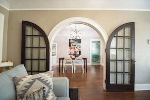 An interior with a dining area, a sofa, and a hallway leading to another room. - Spacious Home with Big Backyard (Little Rock)