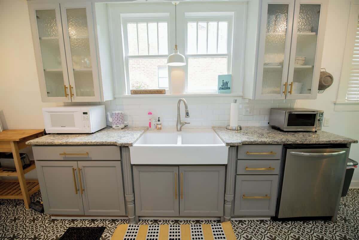A kitchen with a double sink, white cabinets, a microwave, a toaster, and a refrigerator.