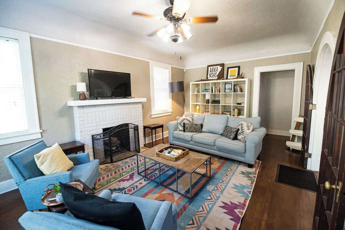 A living room with a fireplace, a television, a bookshelf, and a blue sofa.