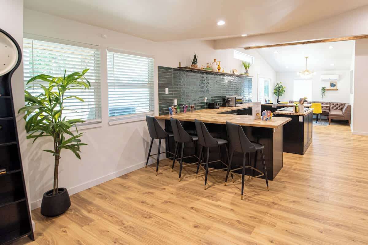 Een moderne keuken met een centraal eiland, barstoelen en een zithoek met een bank.