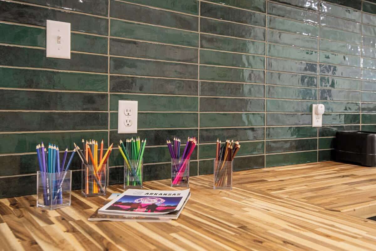A reception area with a wooden floor, green tiled walls, and multiple pencil holders with colored pencils.
