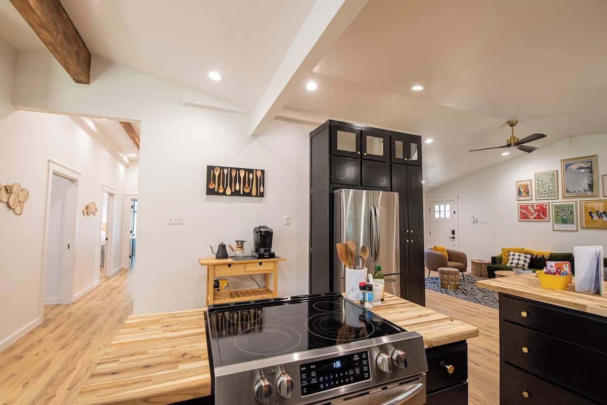 A modern kitchen with a black cabinet, stainless steel appliances, and a wooden countertop.
