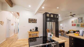 A modern kitchen with a black cabinet, stainless steel appliances, and a wooden countertop.