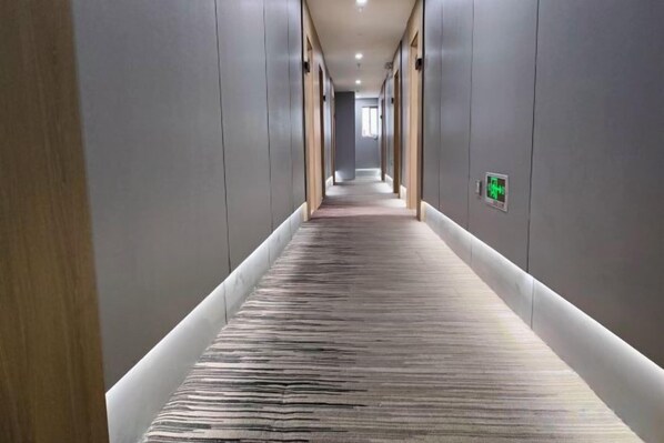 A long, narrow hallway with a patterned carpet and walls on either side. - V Tour Hotel (Shanghai)