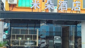 A hotel entrance with a large glass door, a sign above indicating it's a hotel, and a car parked outside. - V Tour Hotel (Shanghai)