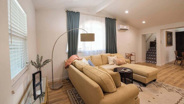 Una sala de estar con un sofá seccional color beige, una mesa de centro redonda y una lámpara de pie.