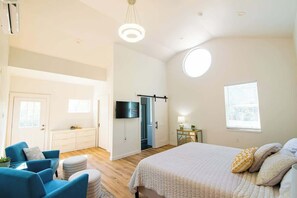 Ein Schlafzimmer mit Bett, Fernseher, Schreibtisch und Fenster.