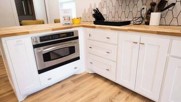 A kitchen with white cabinetry, a wooden countertop, and a built-in oven.