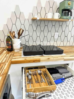 A kitchen counter with a coffee machine, a wooden spoon holder, and a drawer with utensils.