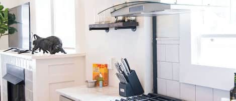 A modern kitchen with a stainless steel stove, oven, and a built-in dishwasher. There are wooden cabinets, a countertop, and a window providing natural light.
