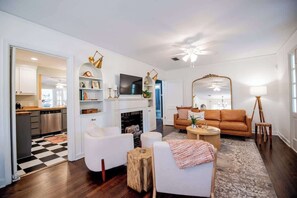 Een moderne woonkamer met een open haard, witte banken, een salontafel en een grote spiegel.