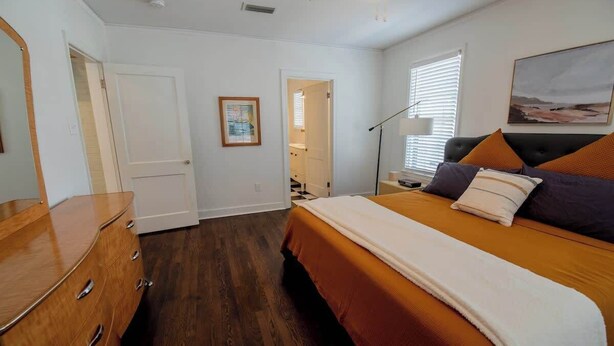 Une chambre à coucher comprenant un lit, une commode et une porte donnant sur une autre pièce.