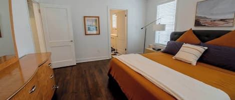 Een slaapkamer met een bed, een kaptafel en een deur naar een andere kamer.