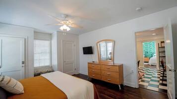 Ein Schlafzimmer mit Bett, Schminktisch, Deckenventilator und einem Schachbrettmuster-Boden.