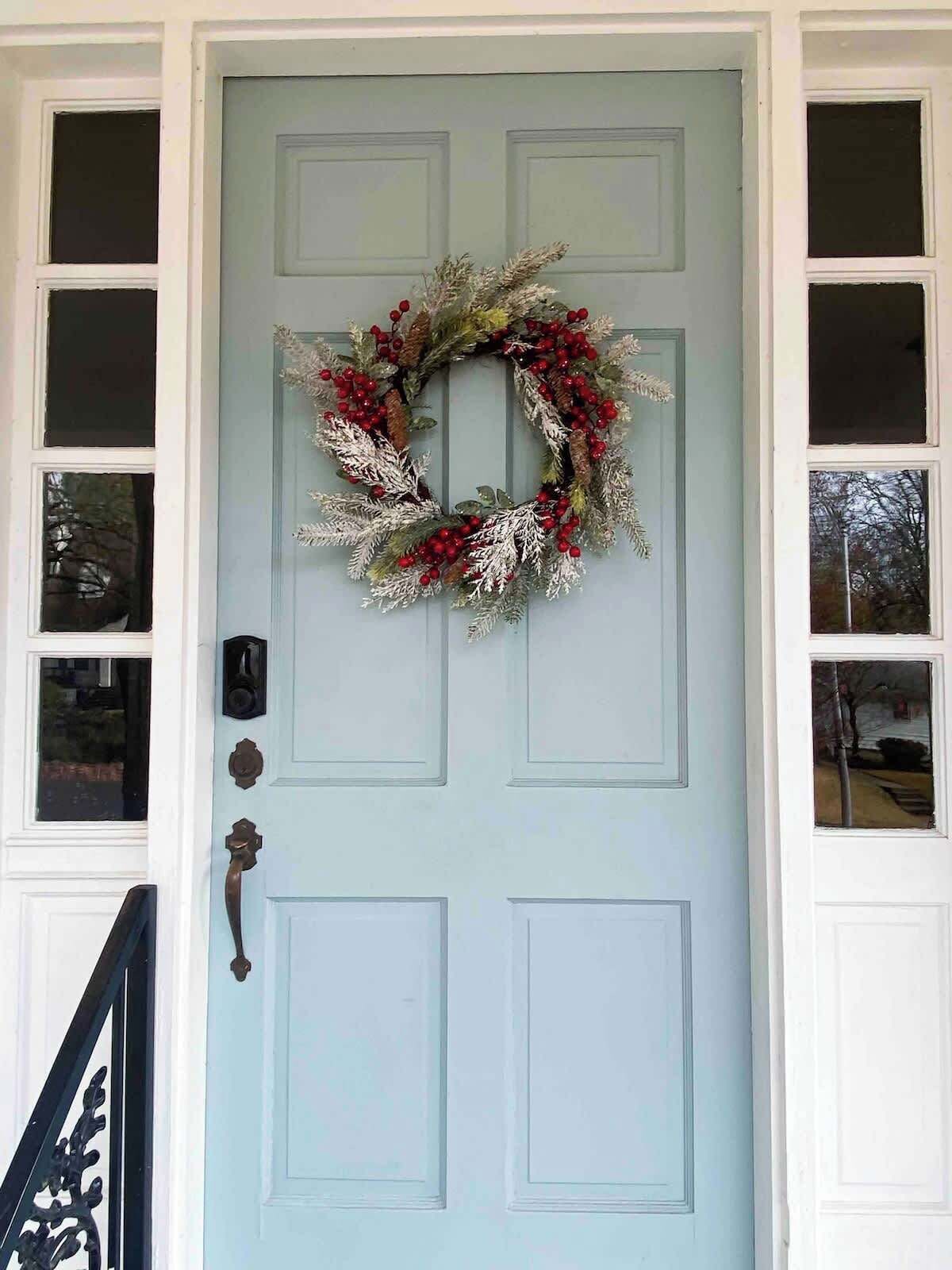 A light blue door with a wreath and a mailbox.