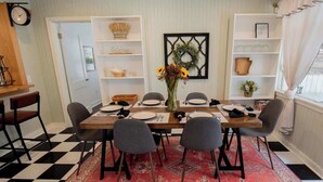 Un coin repas avec un sol à carreaux, une table en bois, quatre chaises et un vase rempli de fleurs.
