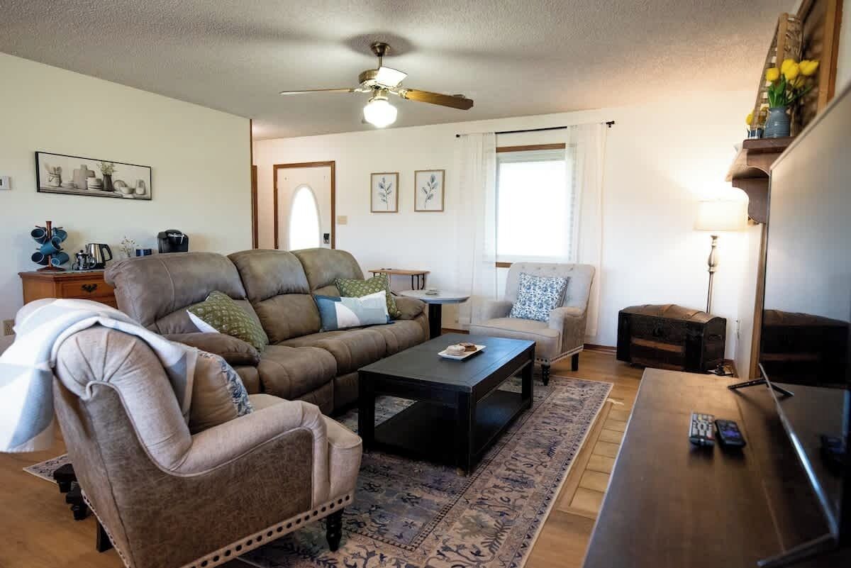 Ein Wohnzimmer mit einer Couch, einem Sessel, einem Couchtisch und einem Fernseher auf einem Schrank.